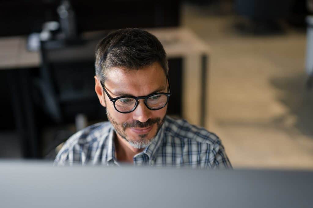 Male worker in glasses sits at his computer screen